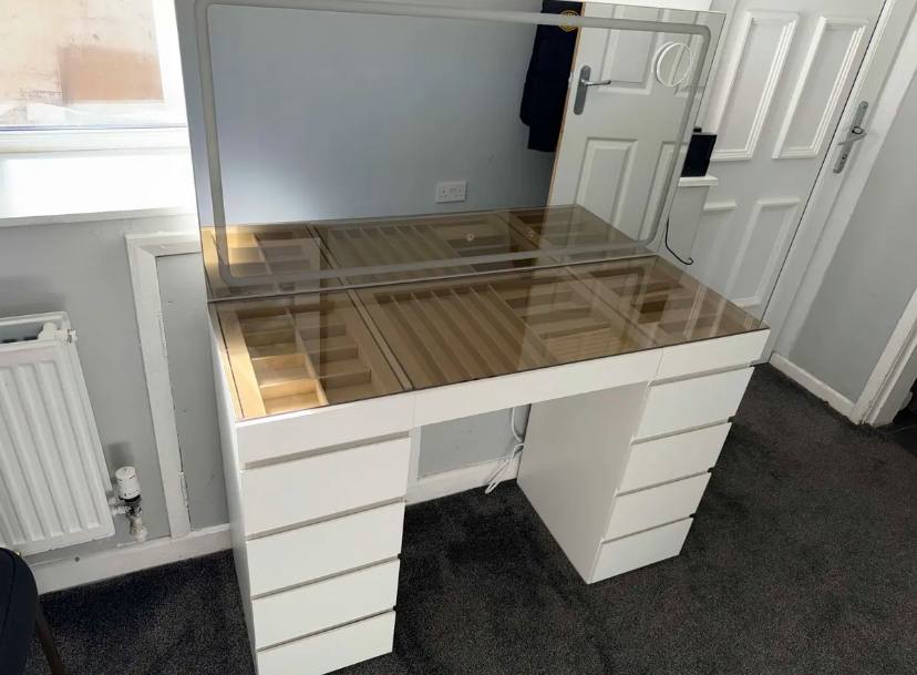 Table de maquillage avec plateau en verre et grand miroir dans une pièce lumineuse